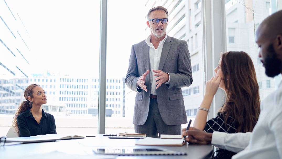 A man executive talking to group of employees during a business meeting at workplace