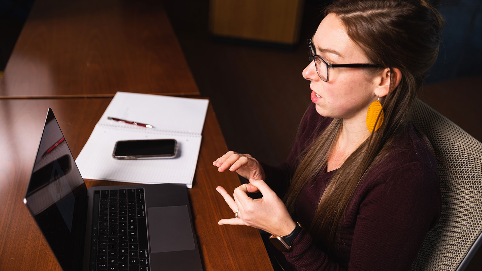 a woman sitting at a desk with a laptop and a phone