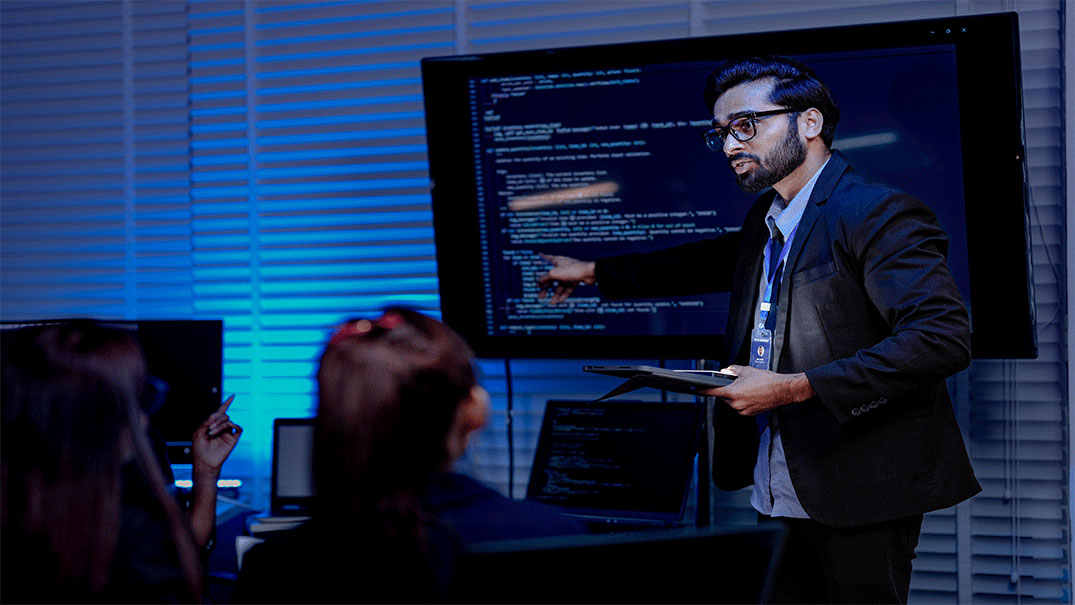 people watching a man explain codes on a monitor