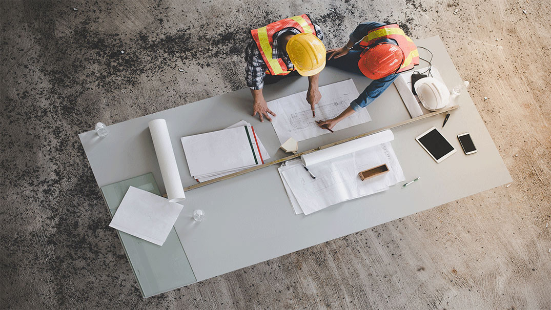 Two engineers working on a blueprint in a construction building