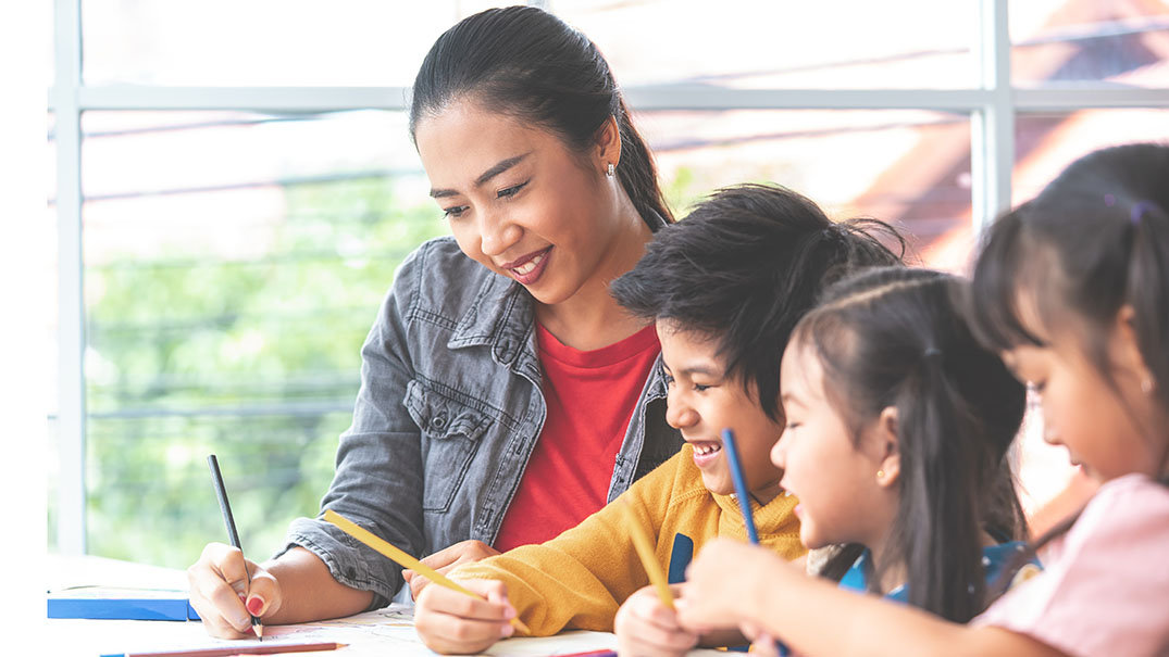 Teacher guiding young children in a classroom learning activity.