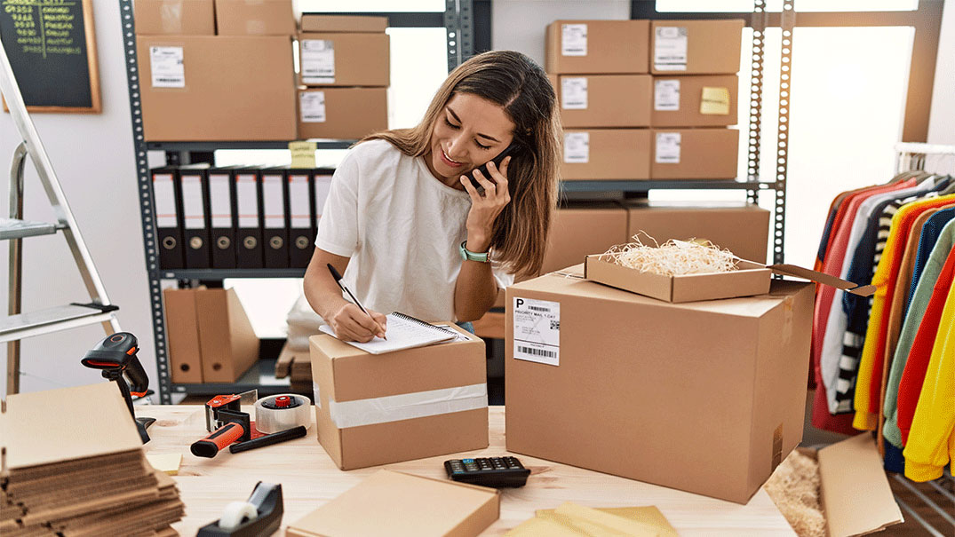 Woman on the phone while filling out paperwork on a box
