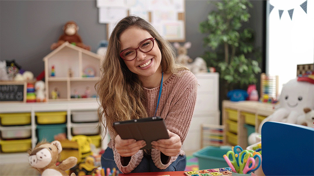 a woman smiling at camera holding a tablet