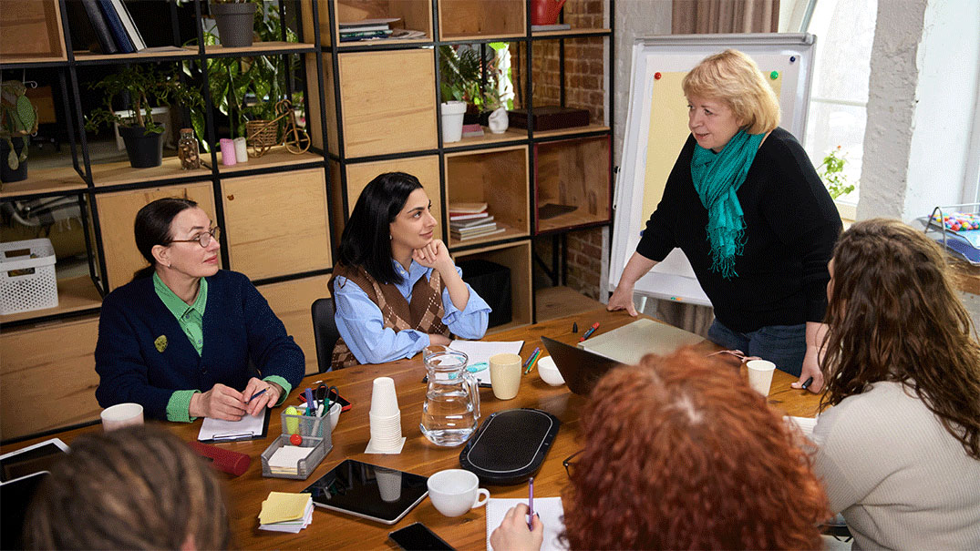 a woman standing in front of a group of people around a table