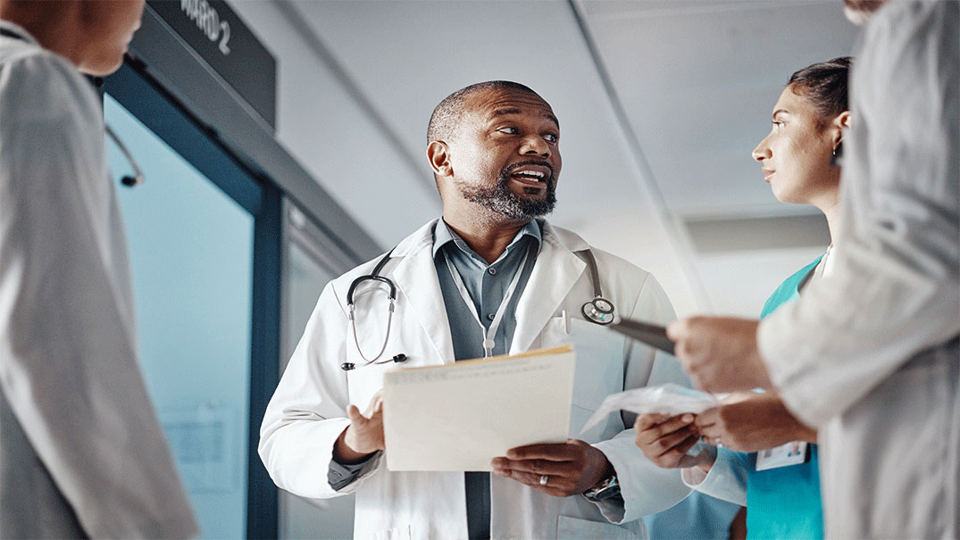 a doctor holding a file speaking with other doctors