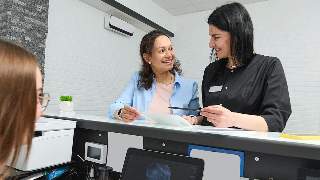 Two women smiling at a medical counter