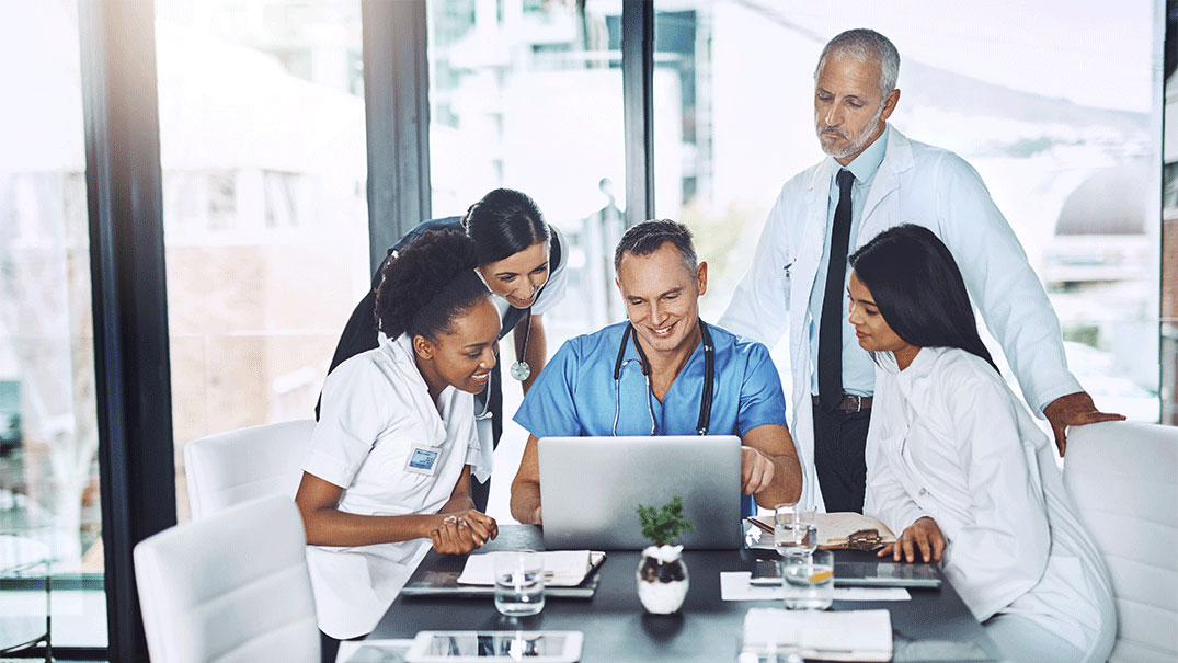 a group of medical professionals around a laptop
