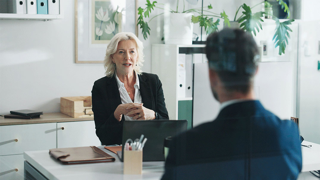 a woman sitting at a desk talking to a man