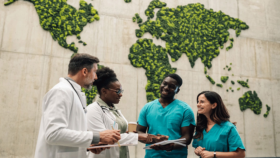 Four medical professionals standing in front of a world map