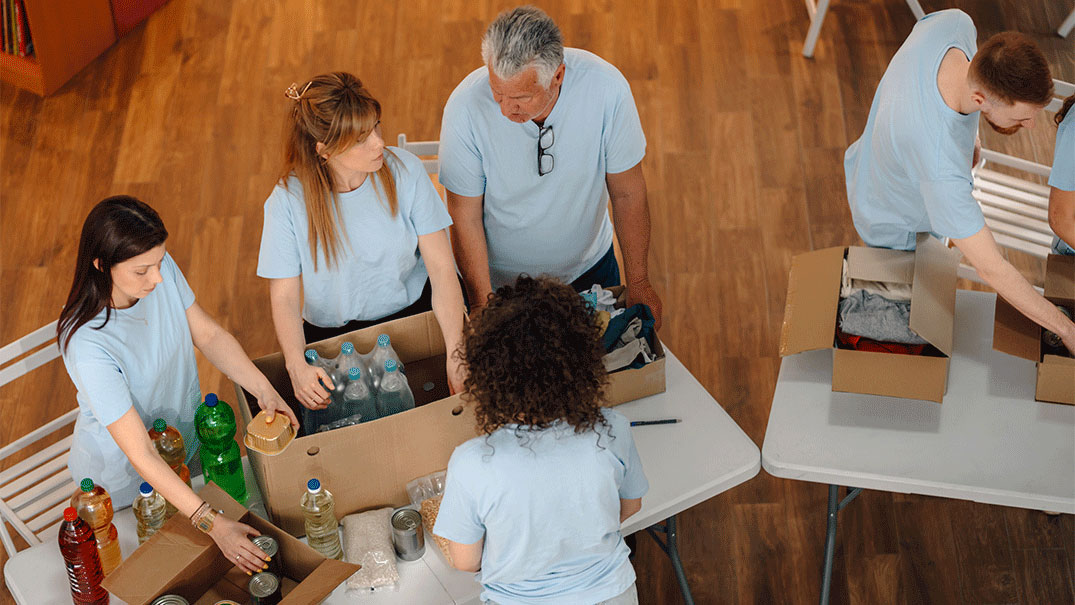 a group of people standing around packing boxes of food