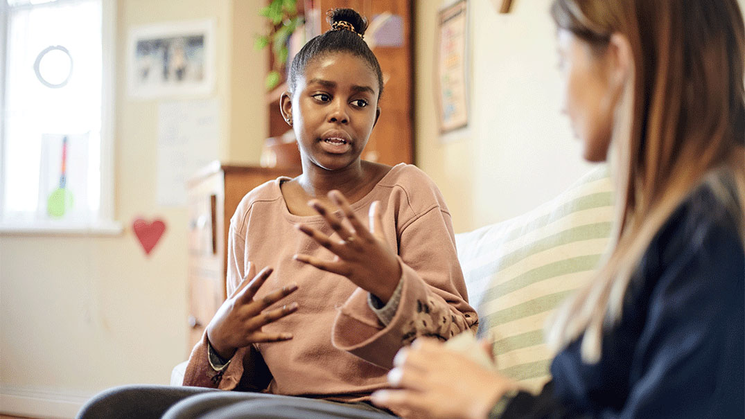a girl sitting on a couch talking with a school counselor