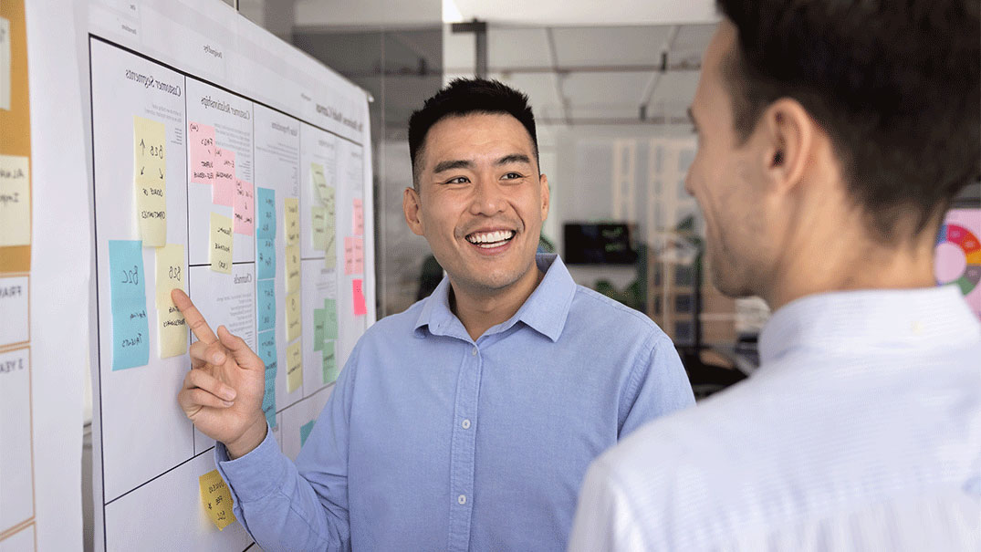 a man pointing at a kanban board with sticky notes