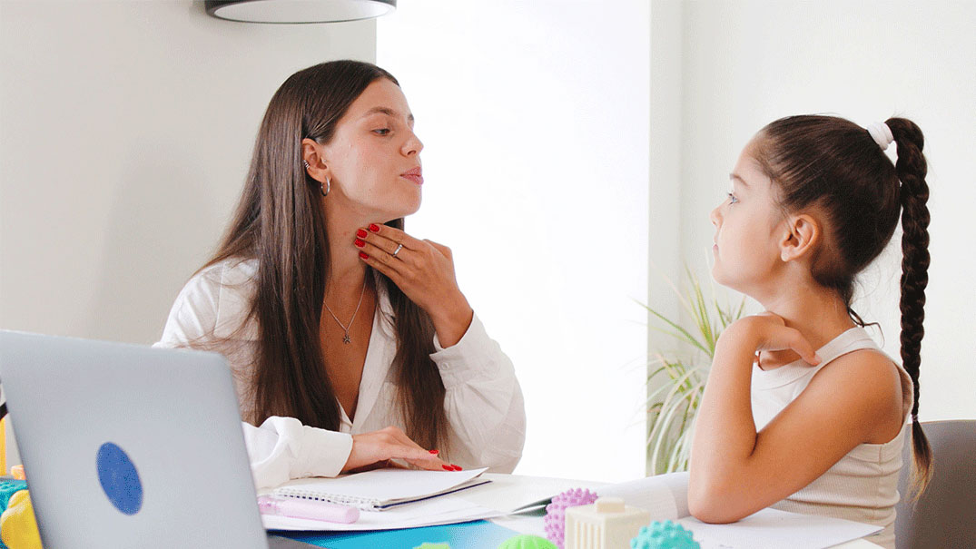 a woman teaching phonetic sounds to a girl facing her