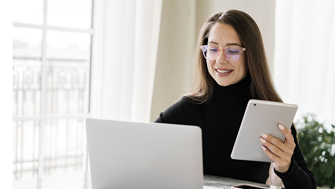 Professional using a laptop and tablet in a remote workspace.