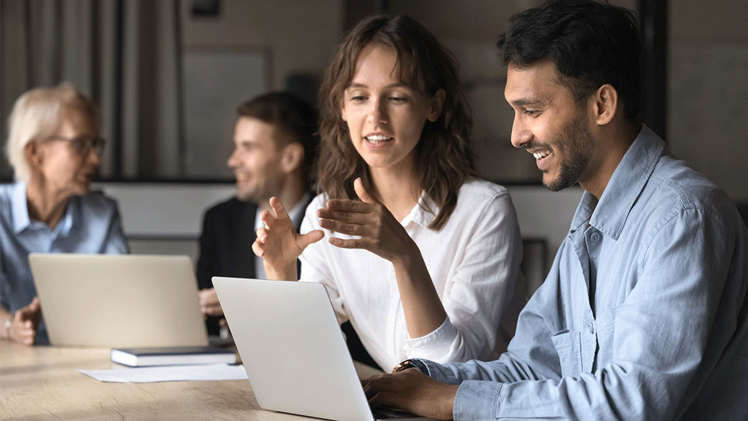 two pairs of people looking at a laptops