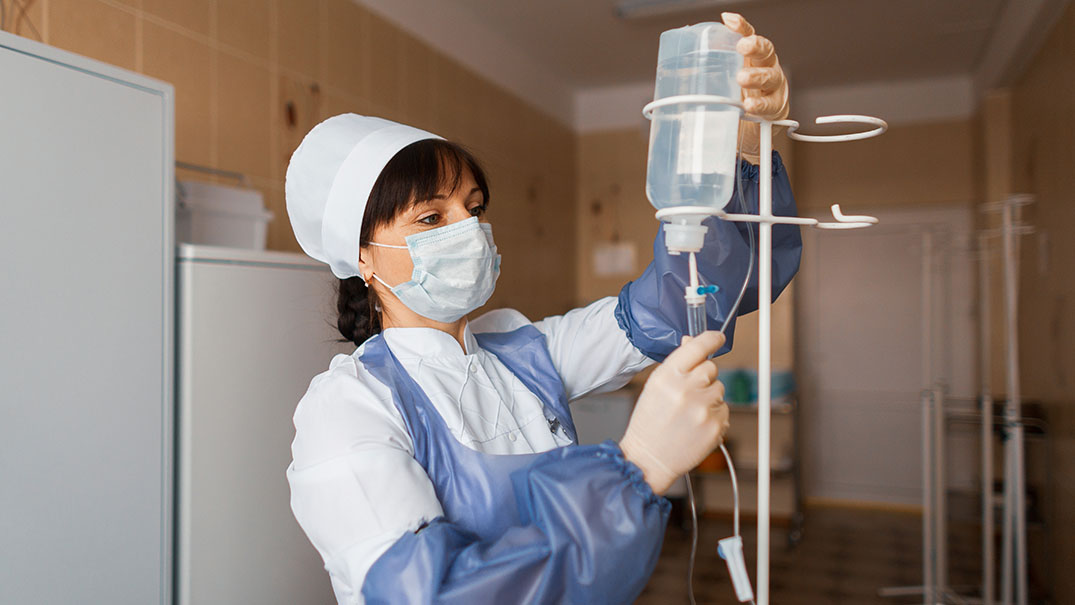 Nurse preparing an IV line in a healthcare setting.